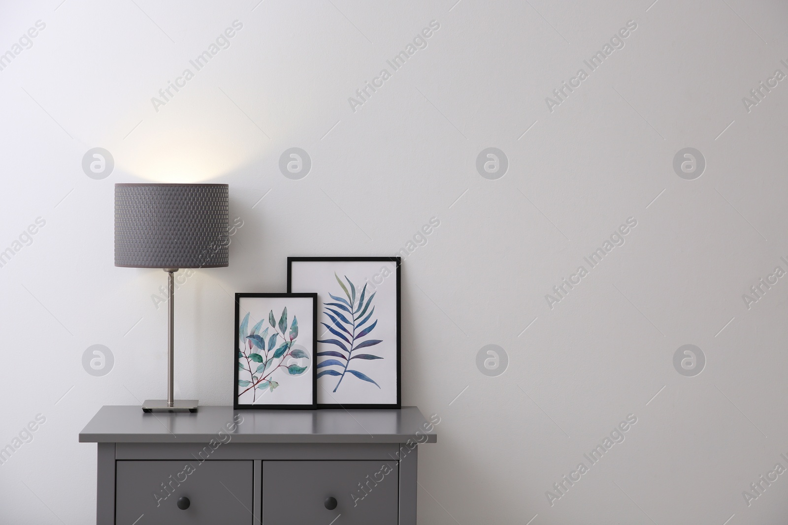 Photo of Modern grey chest of drawers near light wall in room, space for text. Interior design