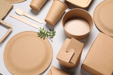 Eco friendly food packaging. Paper containers, tableware and green twigs on light grey background