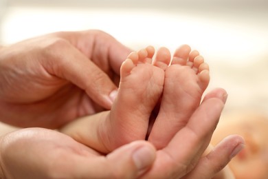 Photo of Father holding his newborn baby, closeup view on feet. Lovely family