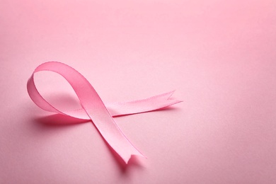 Photo of Pink ribbon on color background, space for text. Breast cancer awareness concept