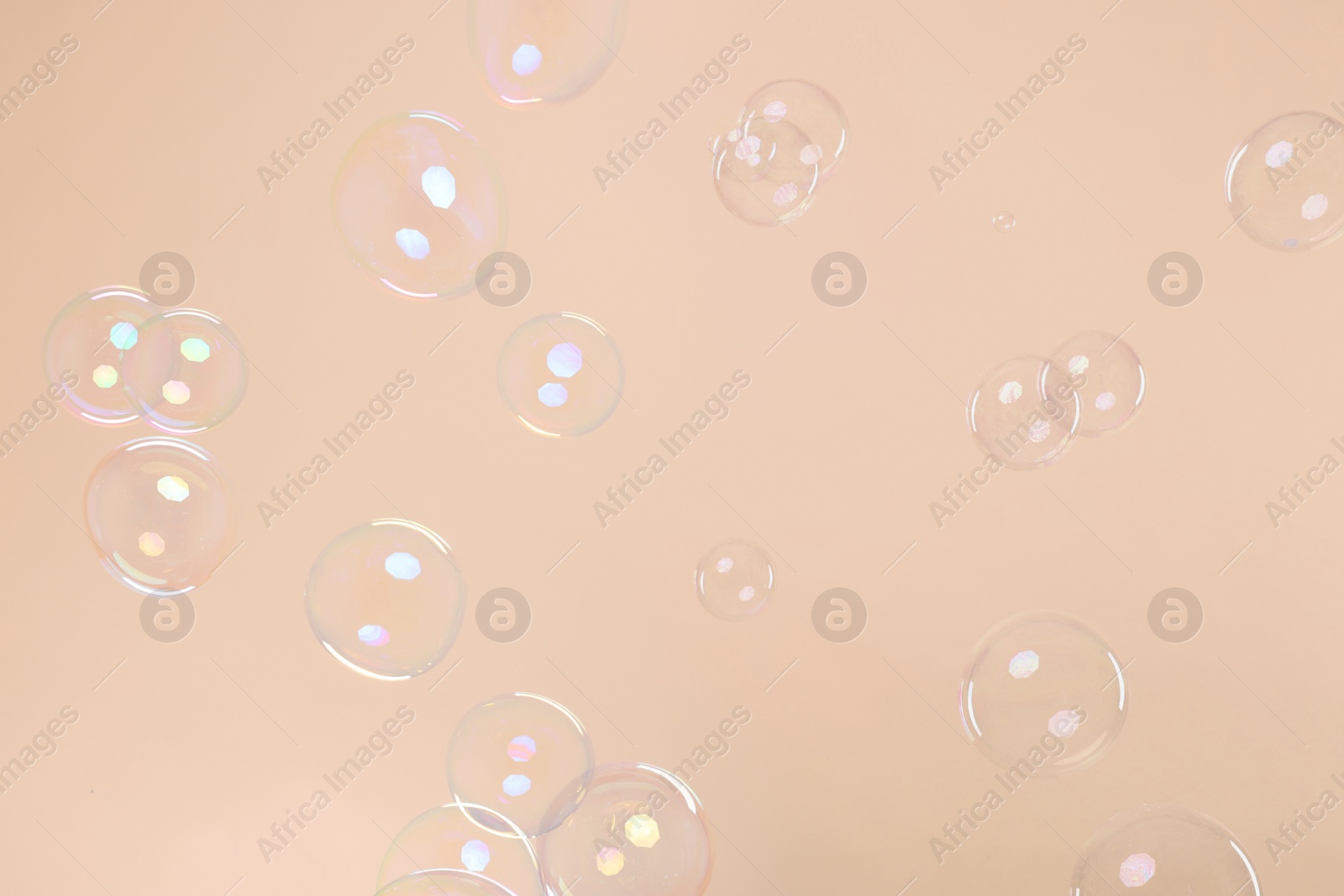 Photo of Many beautiful soap bubbles on beige background. Space for text