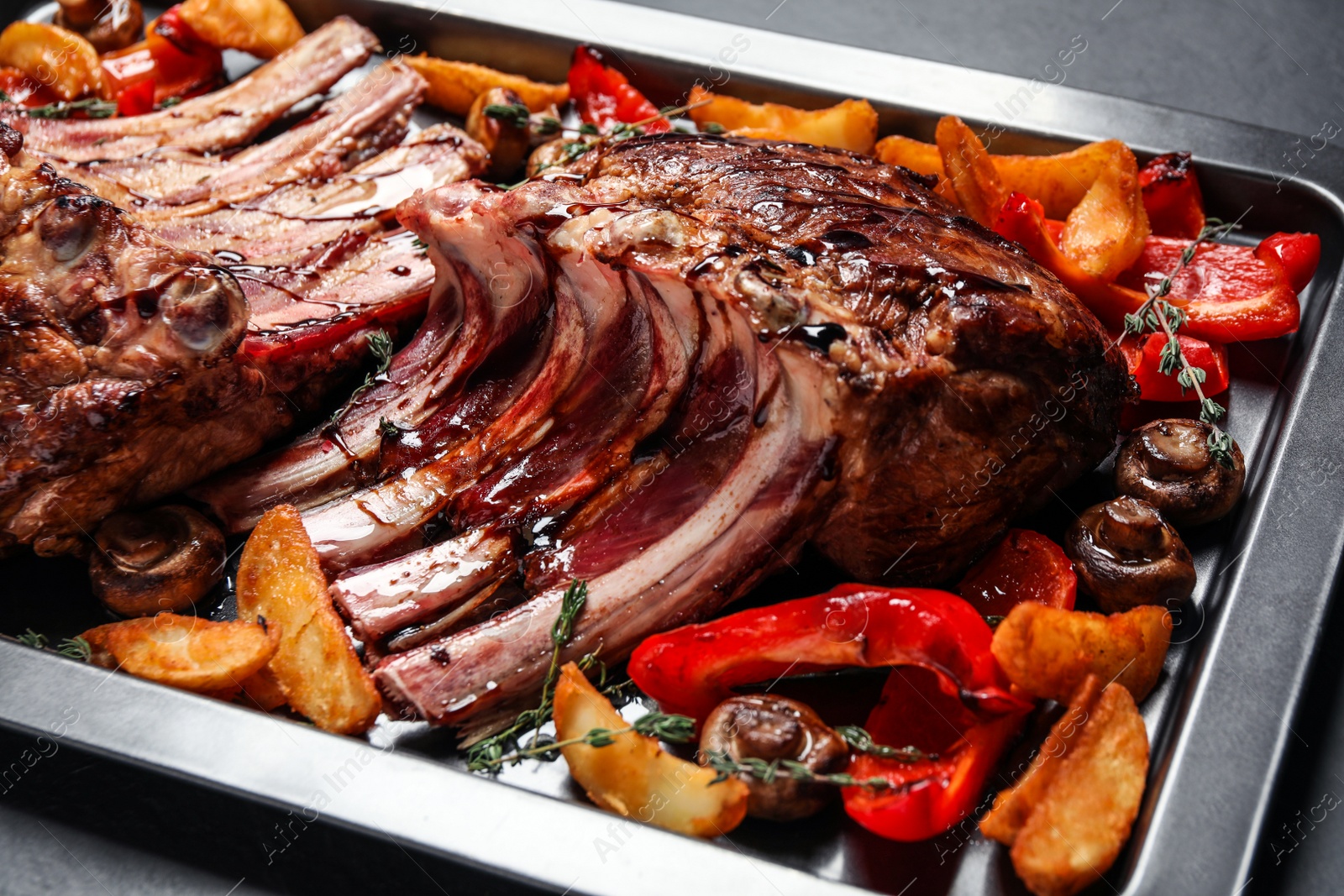 Photo of Delicious roasted ribs with garnish on table, closeup