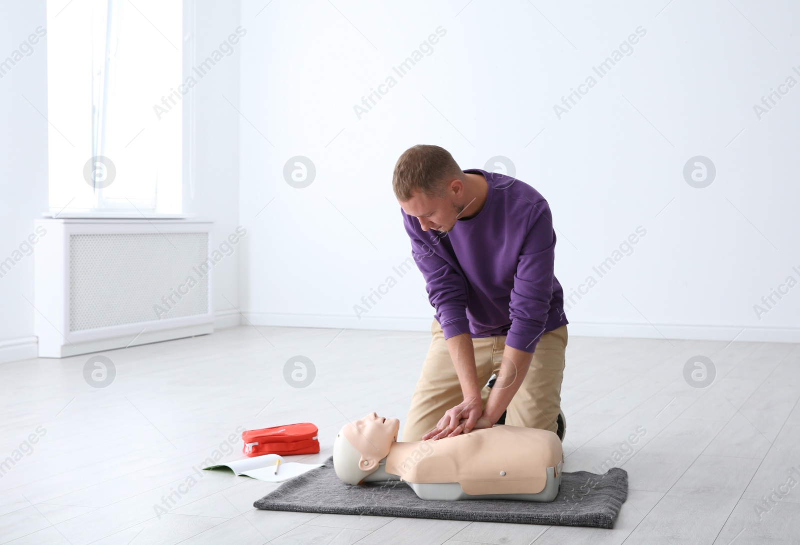 Photo of Man practicing first aid on mannequin indoors