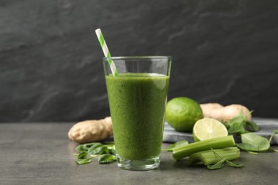 Photo of Green juice and fresh ingredients on grey table