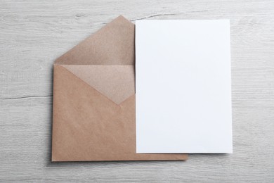 Brown paper envelope with blank card on wooden table, top view. Space for text