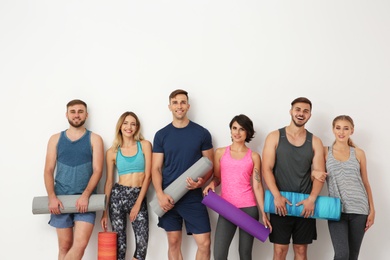 Photo of Group of young people waiting for yoga class on light background