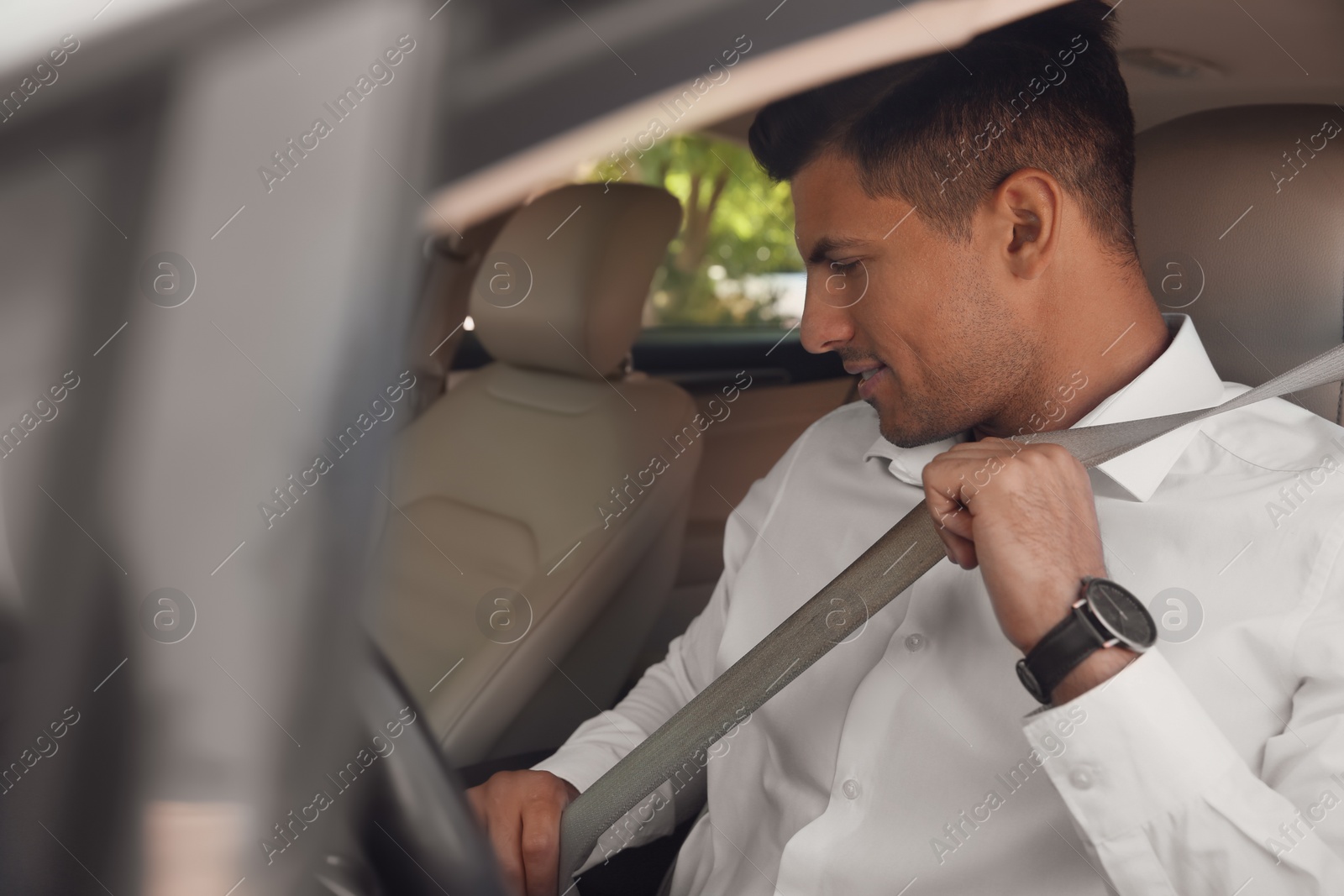 Photo of Male driver fastening safety belt in car