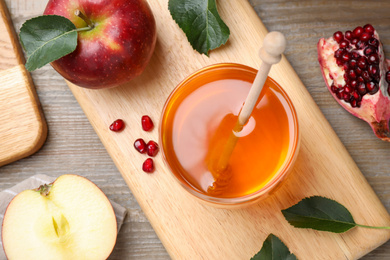 Honey, apples and pomegranate on wooden table, flat lay. Rosh Hashanah holiday