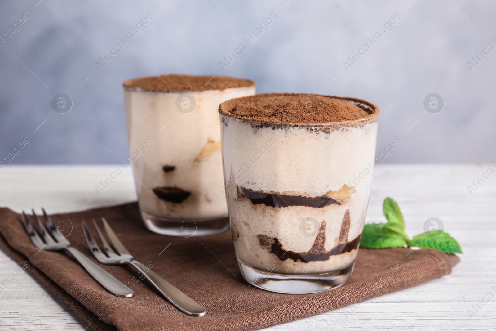 Photo of Two glasses of tiramisu cake on table against color background