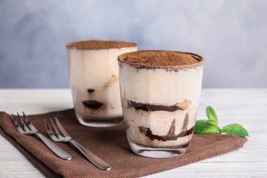 Two glasses of tiramisu cake on table against color background