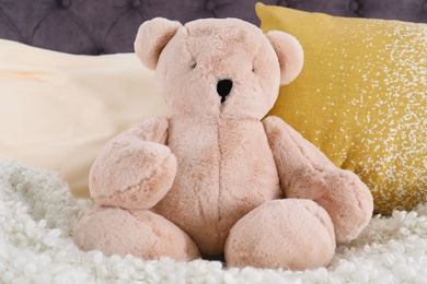 Photo of Cute teddy bear sitting on bed indoors