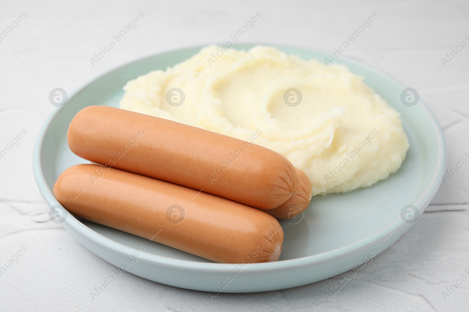 Photo of Delicious boiled sausages and mashed potato on white textured table, closeup