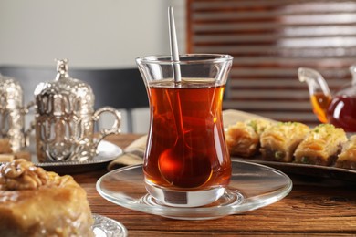 Photo of Turkish tea and sweets served in vintage tea set on wooden table, closeup
