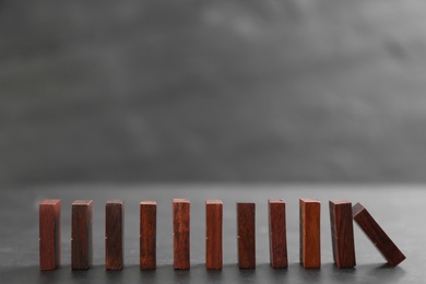 Wooden domino tiles falling on dark grey table. Space for text