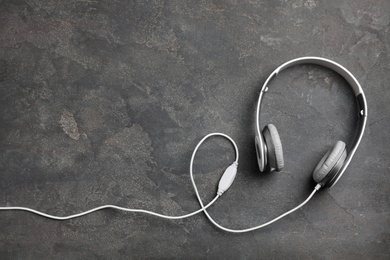 Photo of Stylish modern headphones and space for text on concrete background, top view