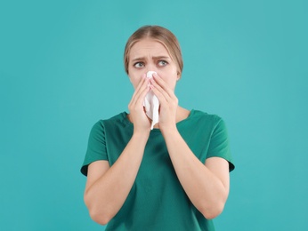 Photo of Young woman suffering from allergy on turquoise background