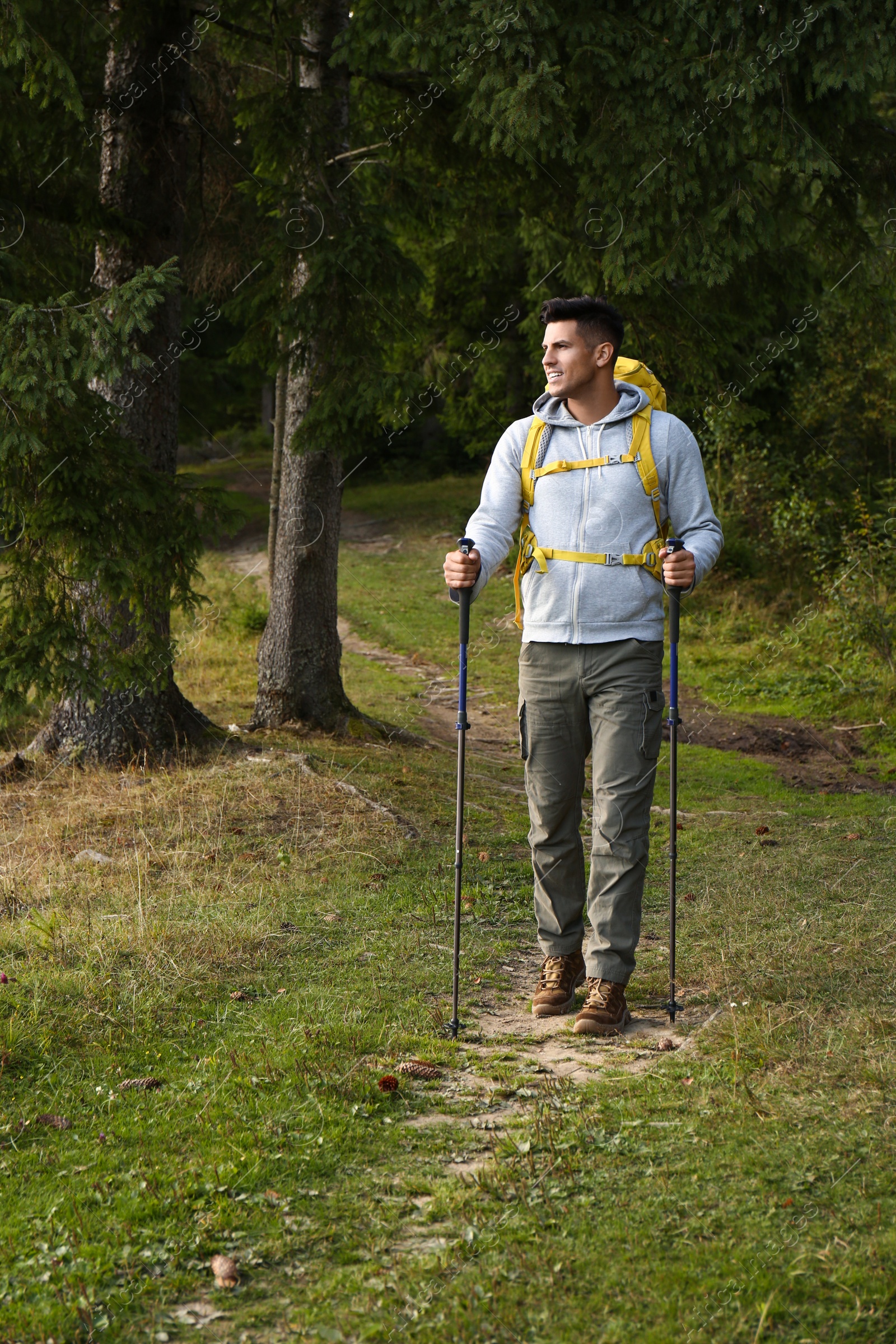 Photo of Man with backpack and trekking poles hiking in forest