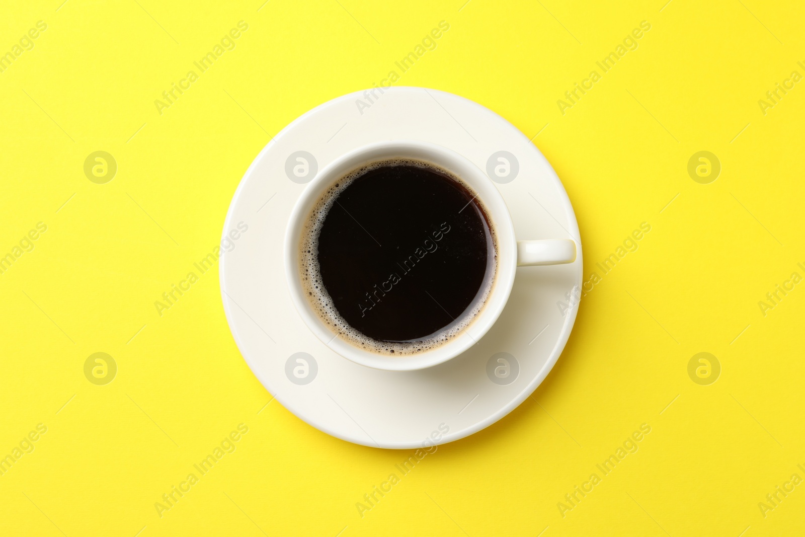 Photo of Cup of aromatic coffee on yellow background, top view