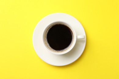 Photo of Cup of aromatic coffee on yellow background, top view