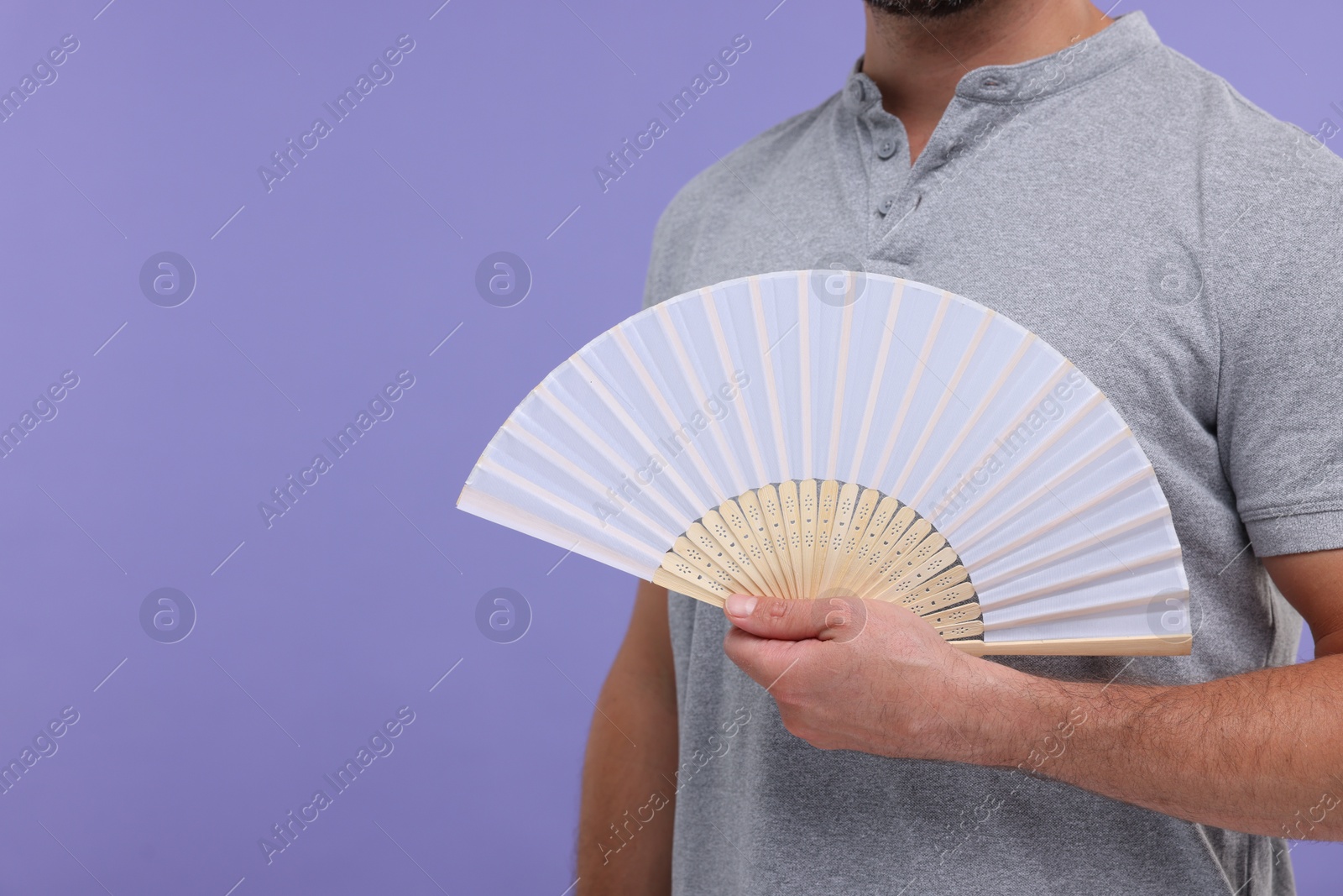 Photo of Man holding hand fan on purple background, closeup. Space for text