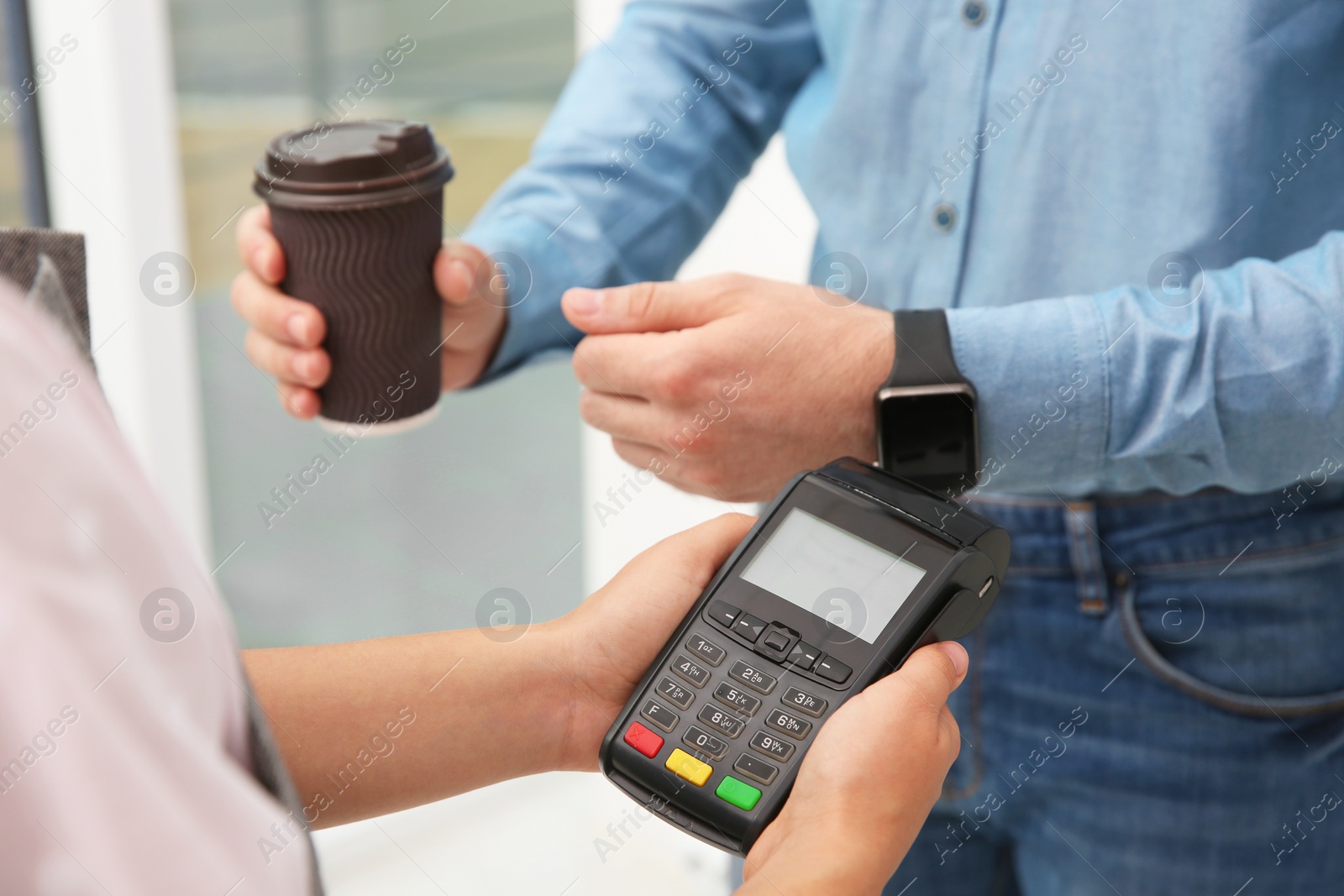 Photo of Man using smart watch for contactless payment via terminal in cafe, closeup