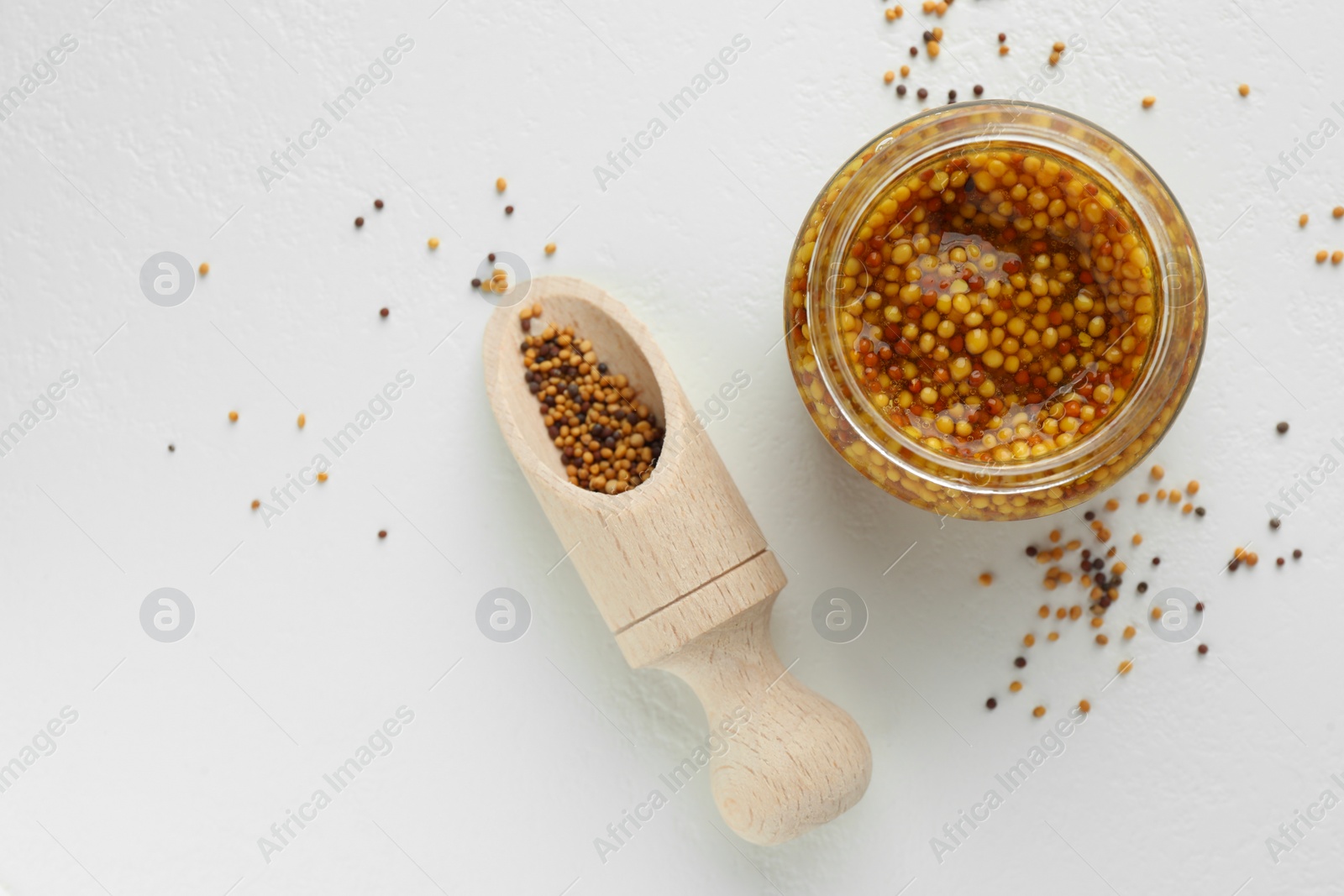 Photo of Fresh whole grain mustard in bowl and dry seeds on white table, flat lay. Space for text