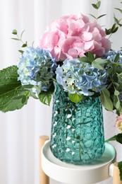 Beautiful hortensia flowers in vase on stand indoors