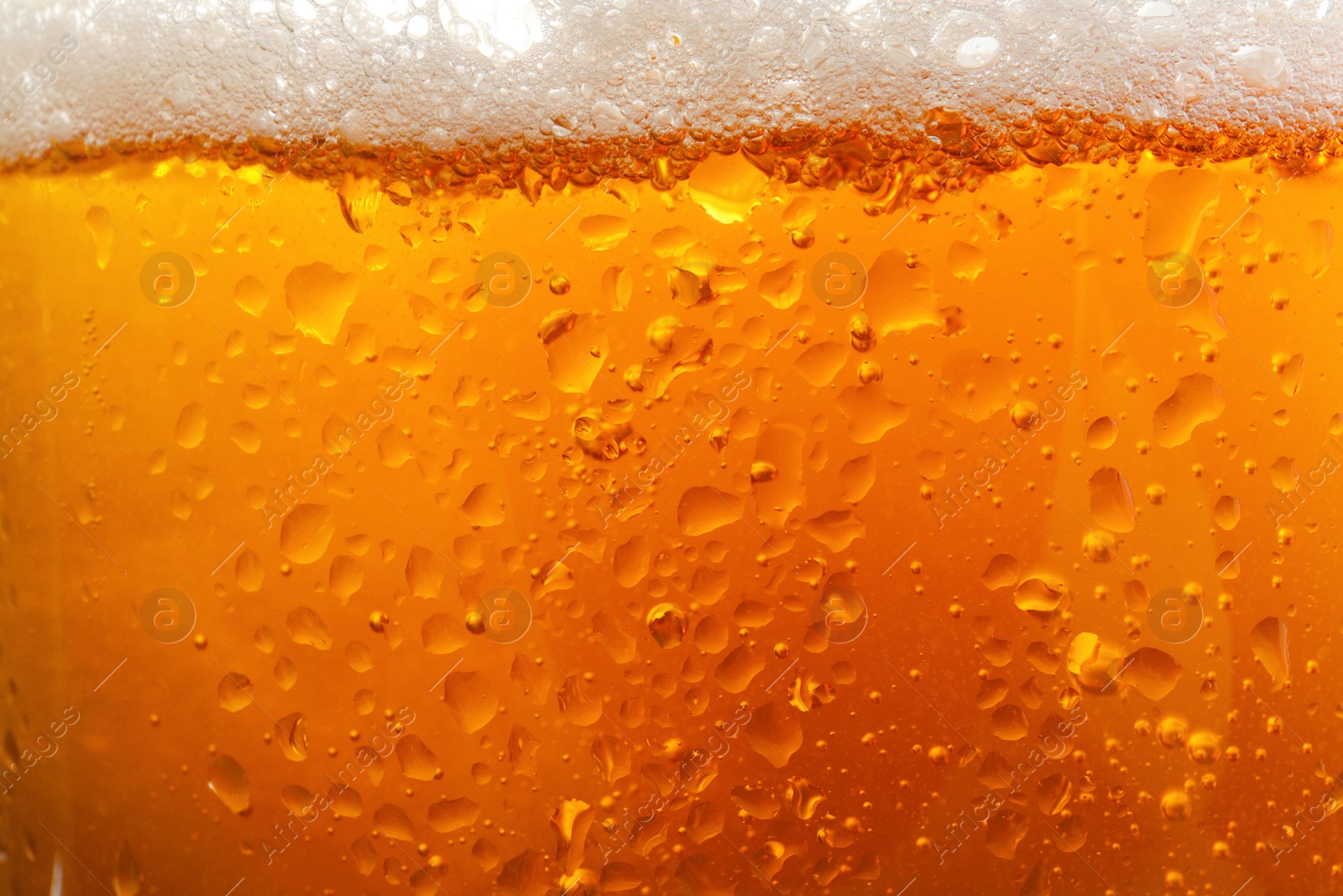 Photo of Glass of tasty cold beer with foam and condensation drops as background, closeup