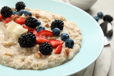 Photo of Tasty oatmeal porridge with berries and almond nuts in plate, closeup