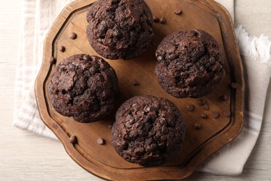 Photo of Delicious chocolate muffins on white wooden table, top view