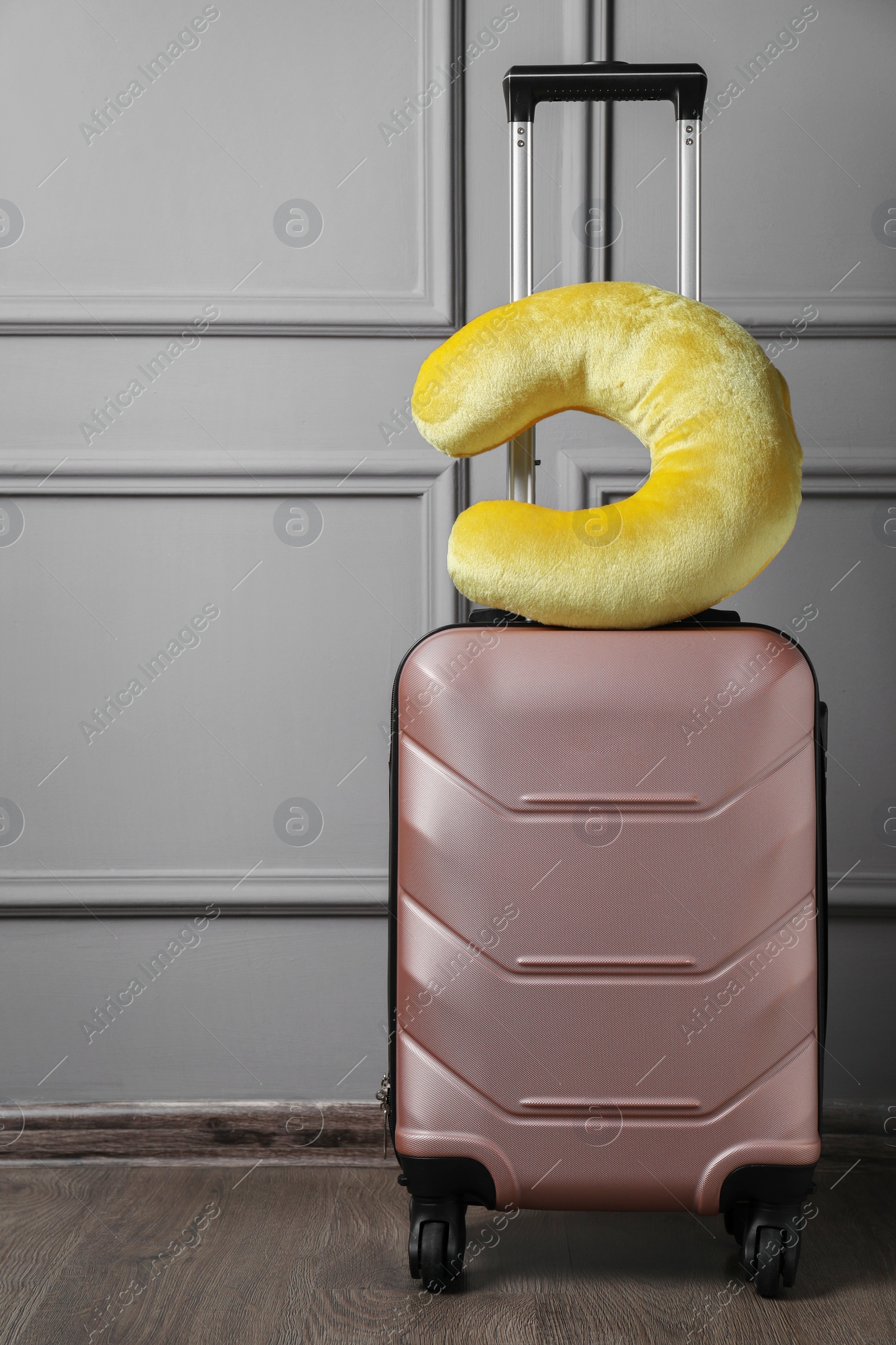 Photo of Yellow travel pillow on suitcase near light wall indoors