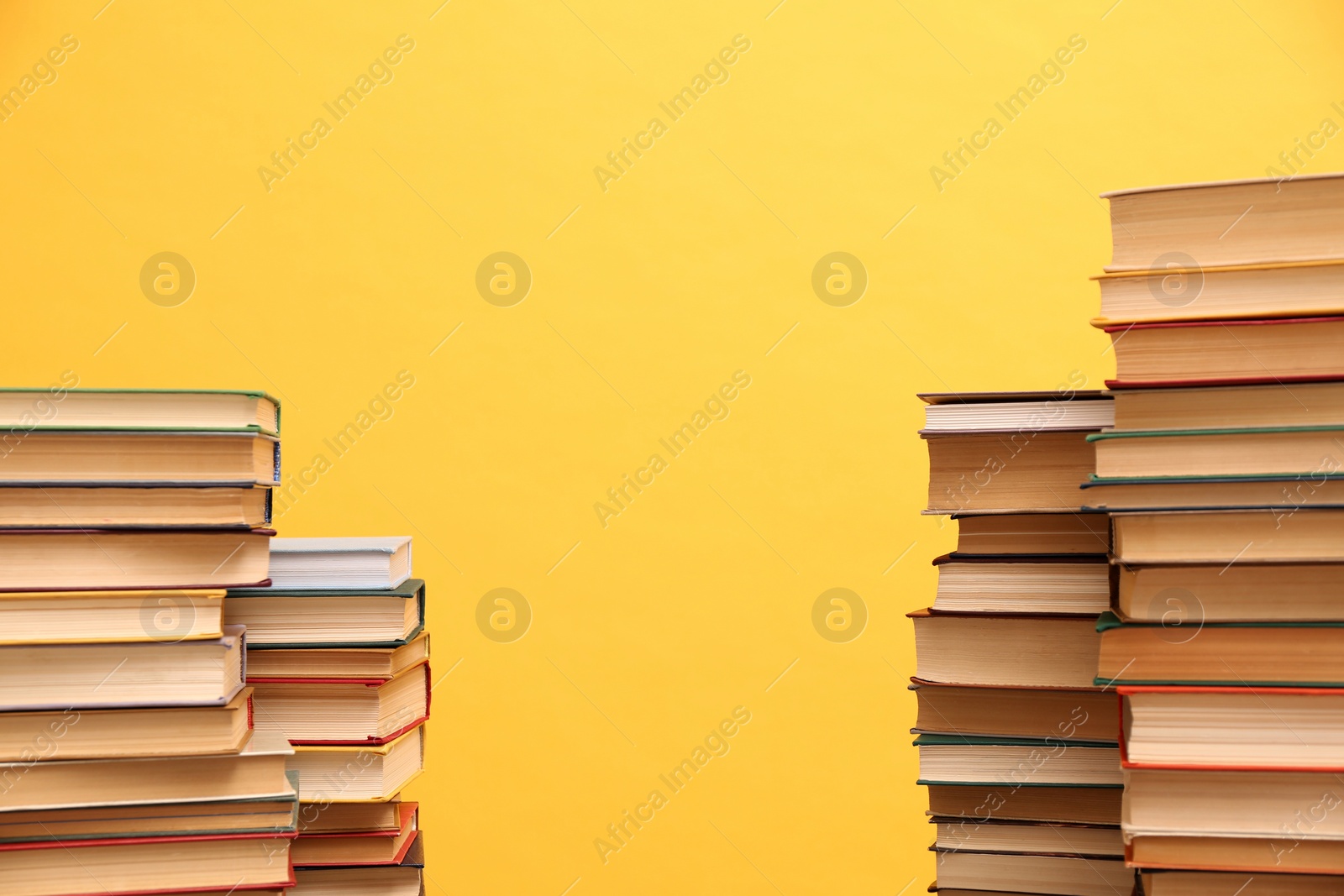 Photo of Many hardcover books on orange background, space for text. Library material