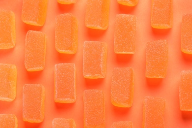 Tasty orange jelly candies on coral background, flat lay