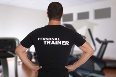 Image of Professional personal trainer in gym, back view