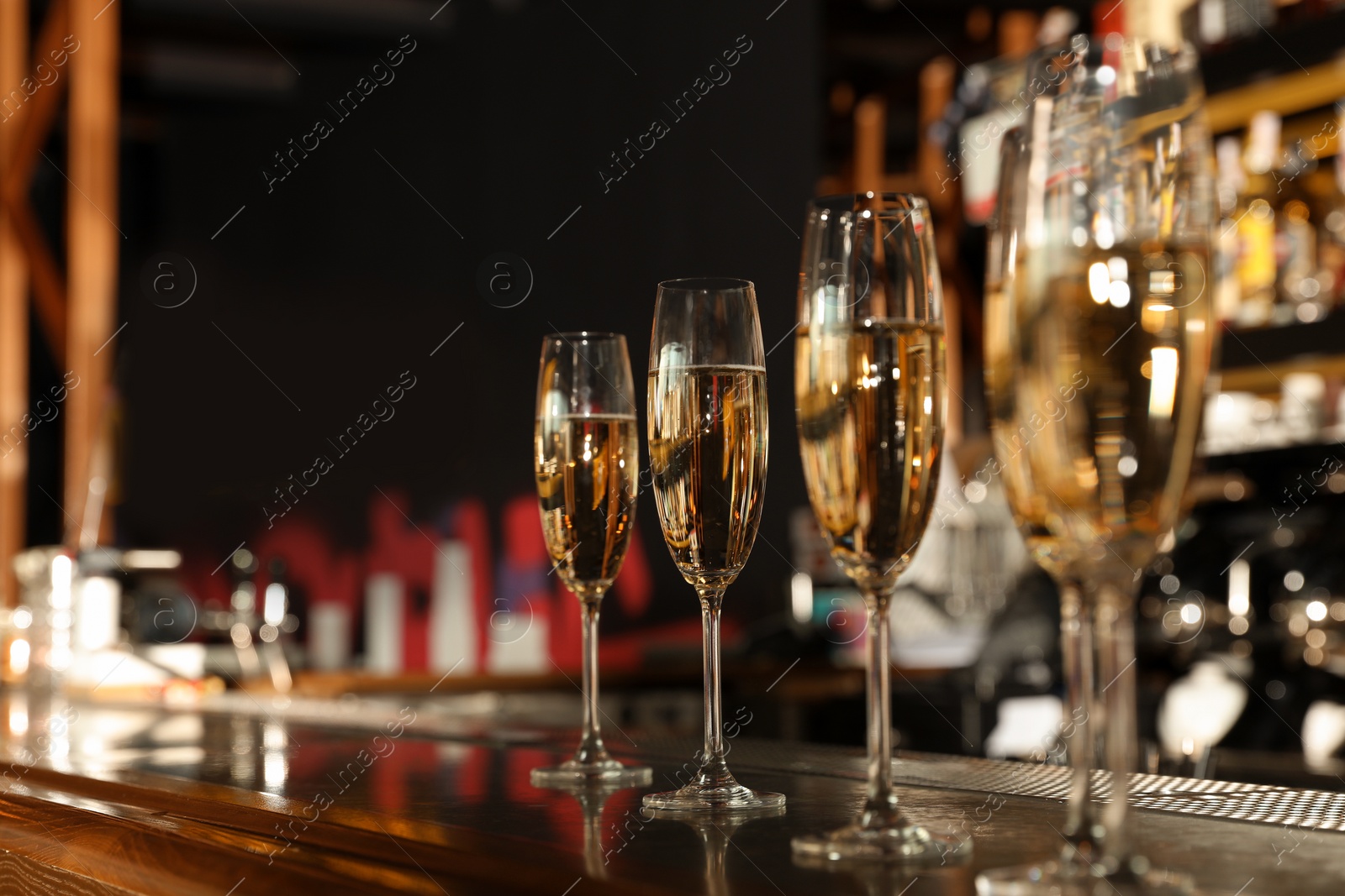 Photo of Glasses of champagne on counter in bar. Space for text