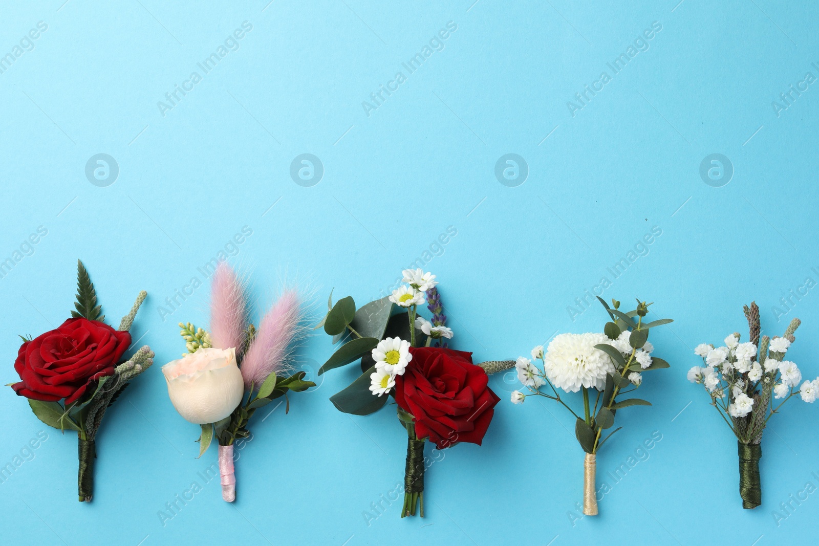 Photo of Many stylish boutonnieres on light blue background, flat lay. Space for text