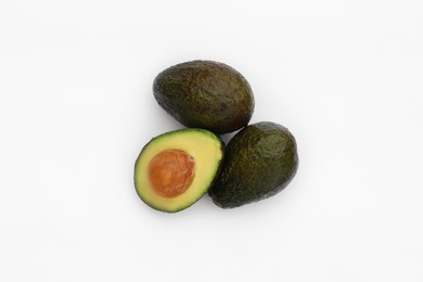 Tasty whole and cut avocados on white background, flat lay