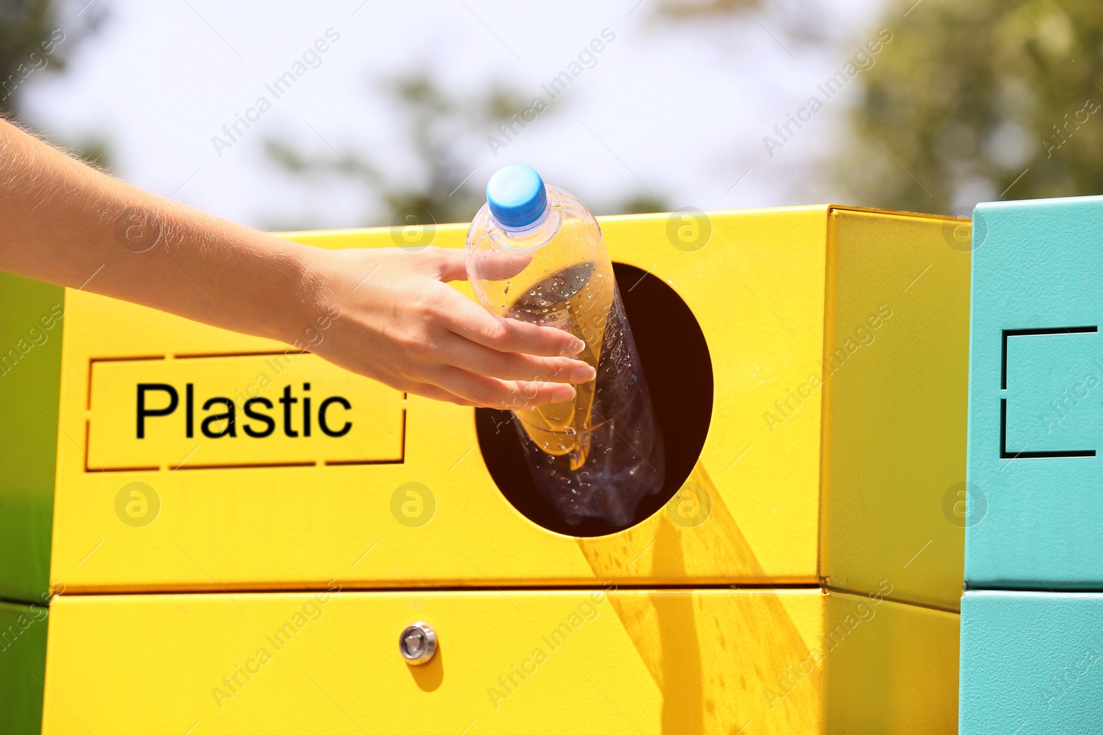 Photo of Woman throwing plastic bottle into sorting bin on city street, closeup. Recycling waste