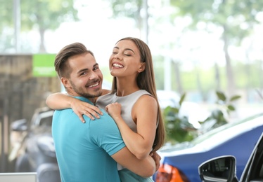 Happy couple buying new car in salon