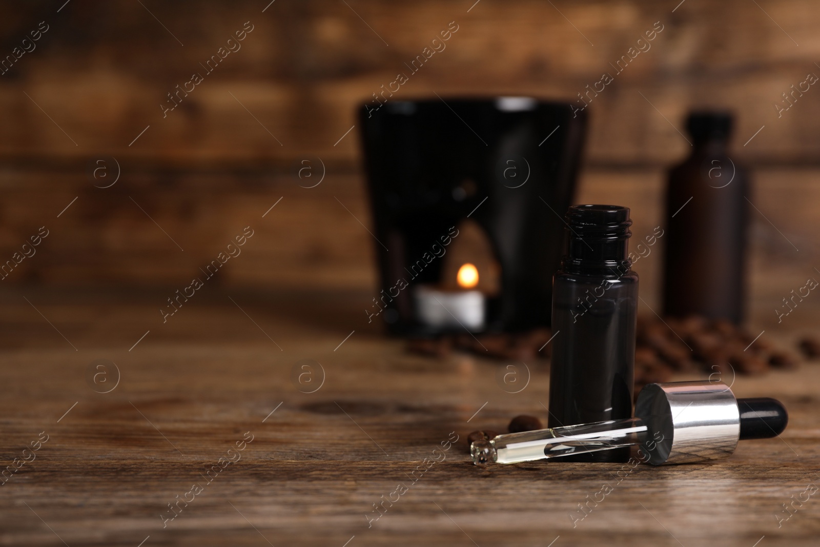 Photo of Aroma lamp and coffee essential oil on wooden table, space for text