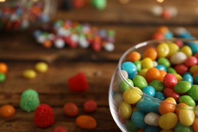 Delicious dragee in bowl on wooden table, closeup. Space for text