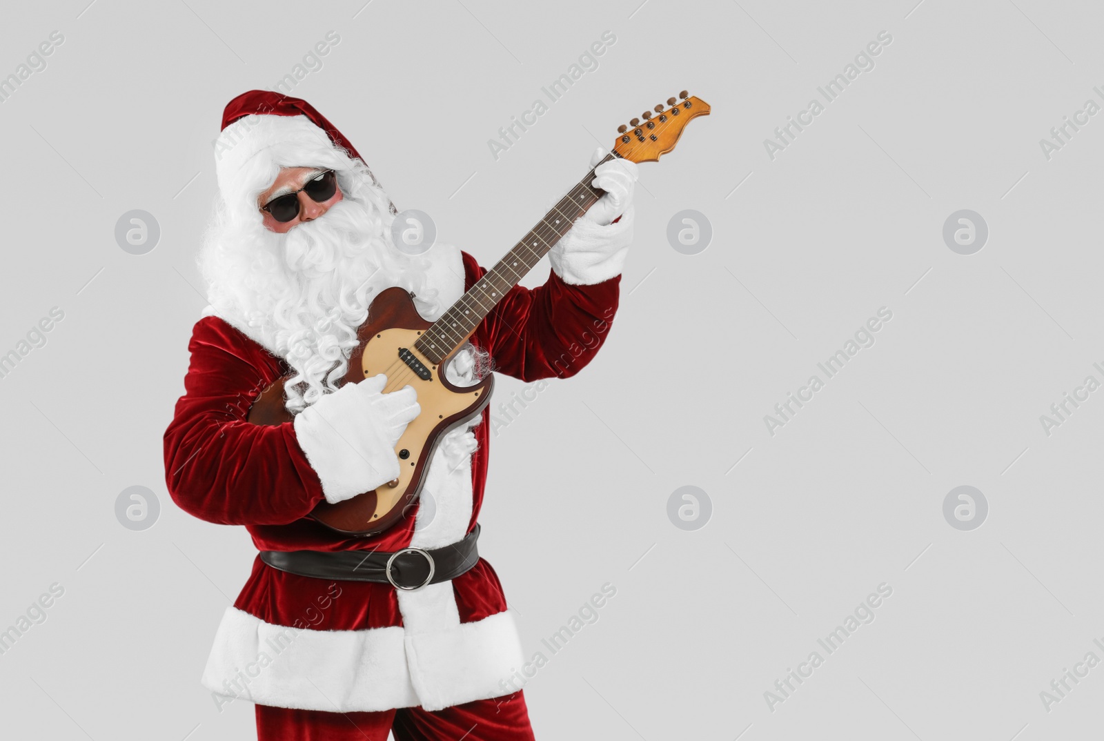 Photo of Santa Claus playing electric guitar on light grey background, space for text. Christmas music