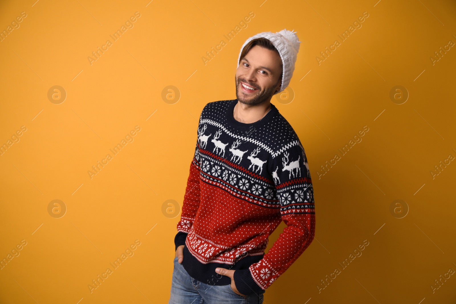 Photo of Young man in Christmas sweater and hat on yellow background