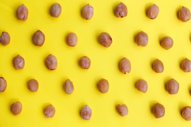 Photo of Tasty organic hazelnuts on yellow background, flat lay