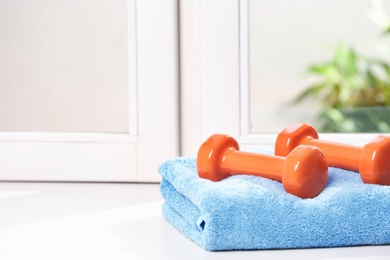 Towel with vinyl dumbbells on windowsill, space for text