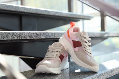 Photo of Pair of stylish women's sneakers on grey marble stairs indoors