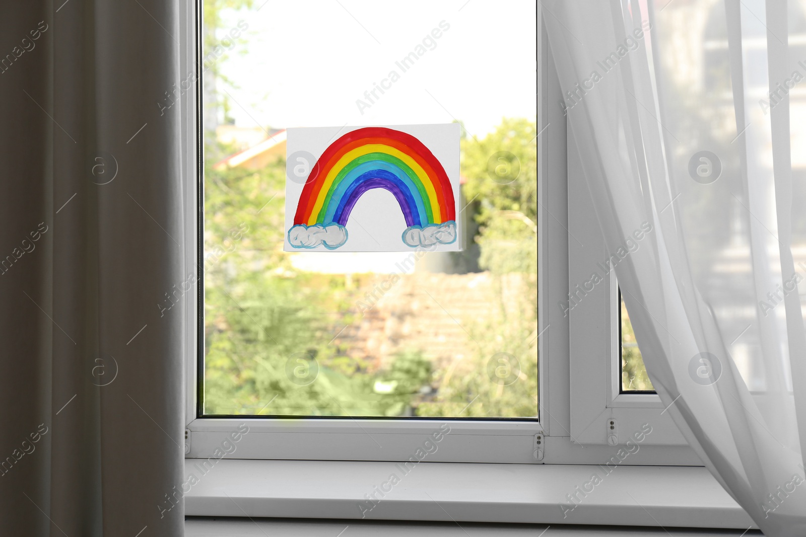 Photo of Picture of rainbow on window glass indoors. Stay at home concept