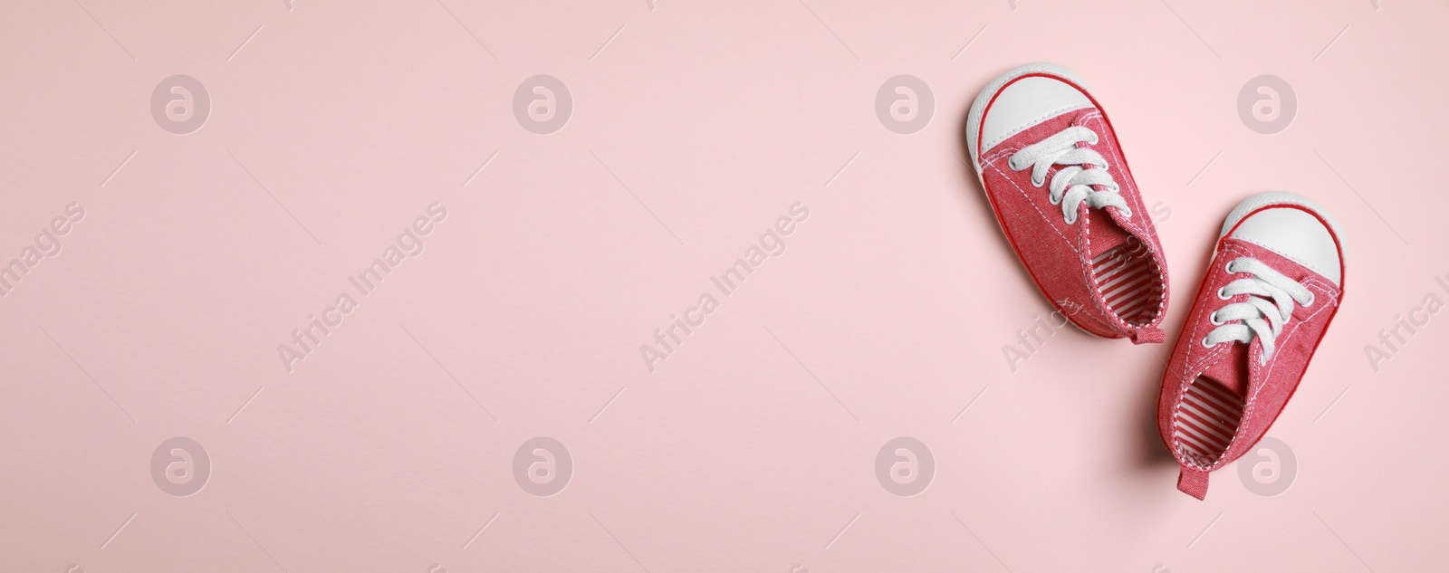 Image of Cute baby shoes on beige background, top view. Banner design with space for text