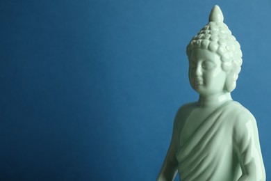 Photo of Beautiful ceramic Buddha sculpture on blue background. Space for text