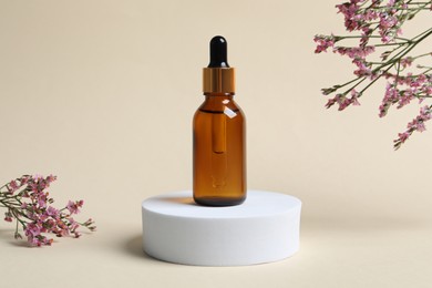 Photo of Bottle of cosmetic oil and flowers on beige background